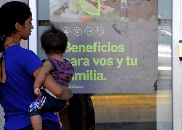 Mujer con bebe en brazos mirando afiche