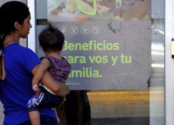 Mujer con bebe en brazos mirando afiche